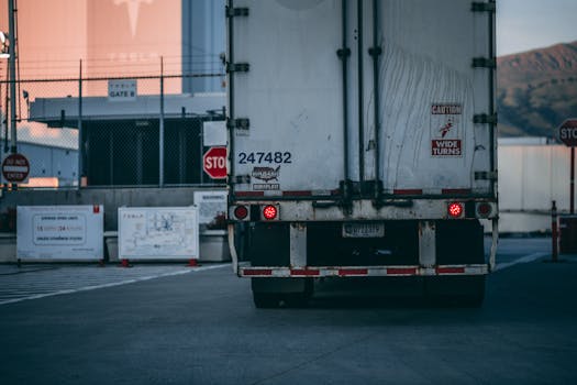 Home Semi truck parked at a loading dock with visible caution signs and industrial surroundings.