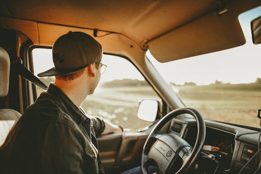 Home A man enjoys a relaxed drive through the countryside on a sunny day, looking out onto the scenery.